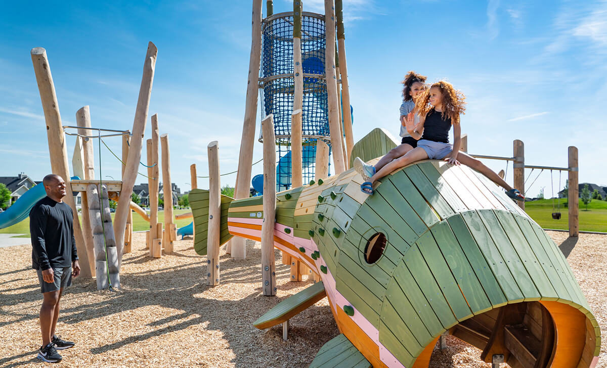 Girls playing on playground as father watches